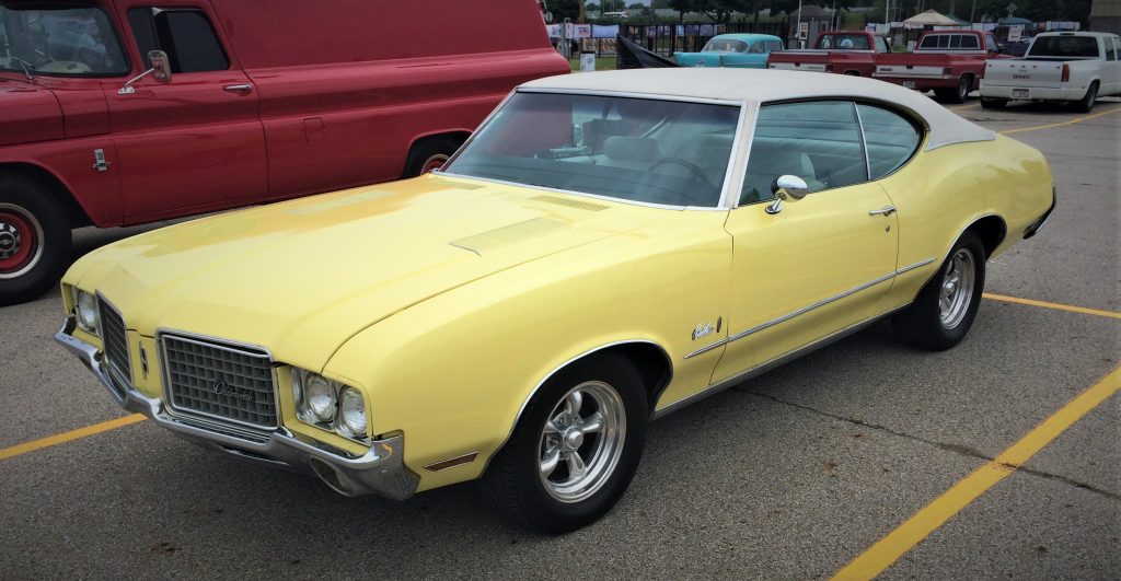 yellow oldsmobile cutlass fastback coupe parked at a car show