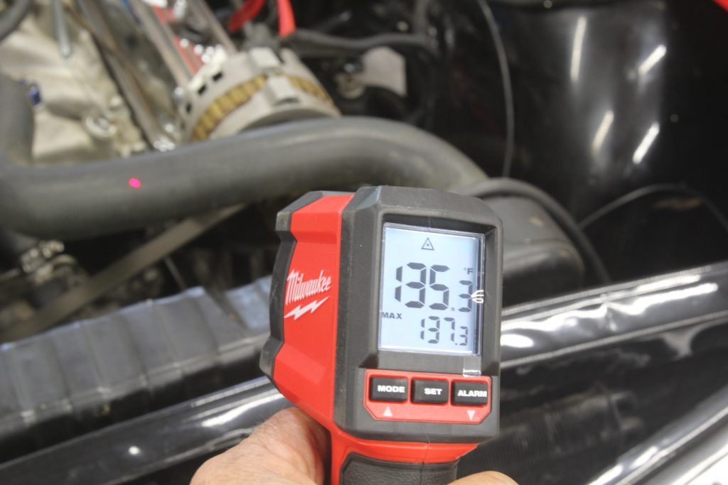 person using infrared temperature heat gun to read temps on an engine