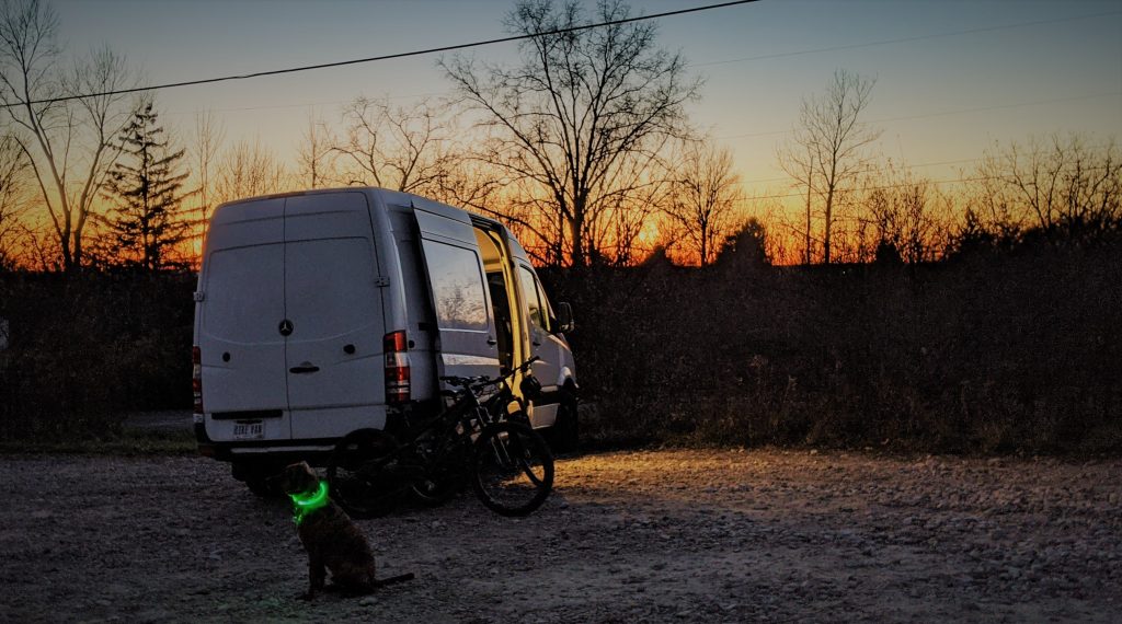 Vanlife van at sunset at campsite with mountain bike and dog