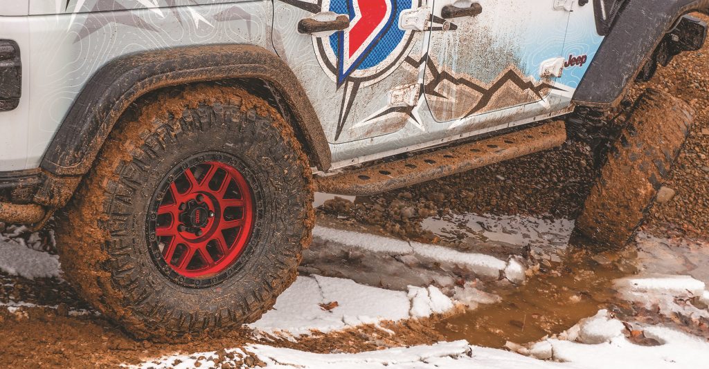 close-up of fishbone off road rock sliders bolted on a Jeep Wrangler Unlimited in mud