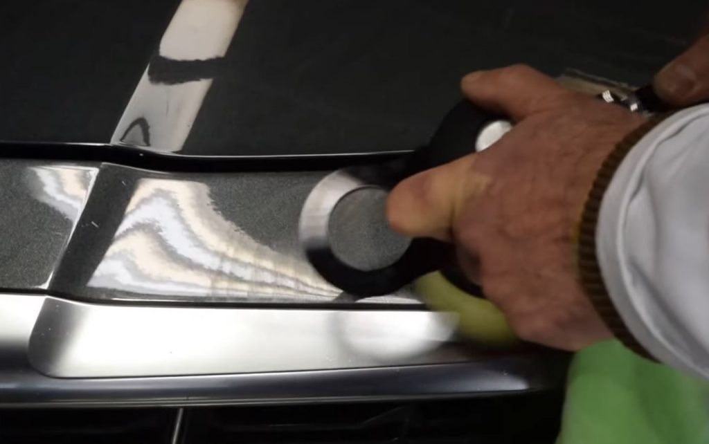 man polishing out a paint scratch on a car hood