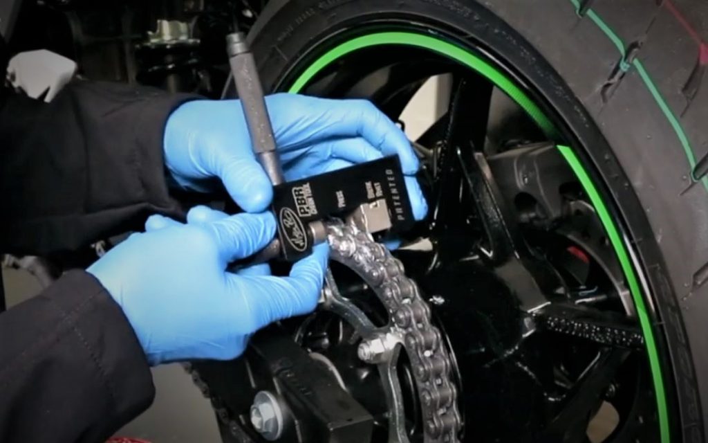 chain rivet tool being used to press on master link of motorcycle chain