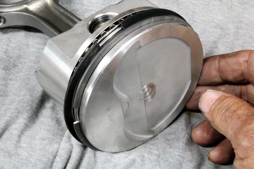man fitting gas ported piston rings on a piston head