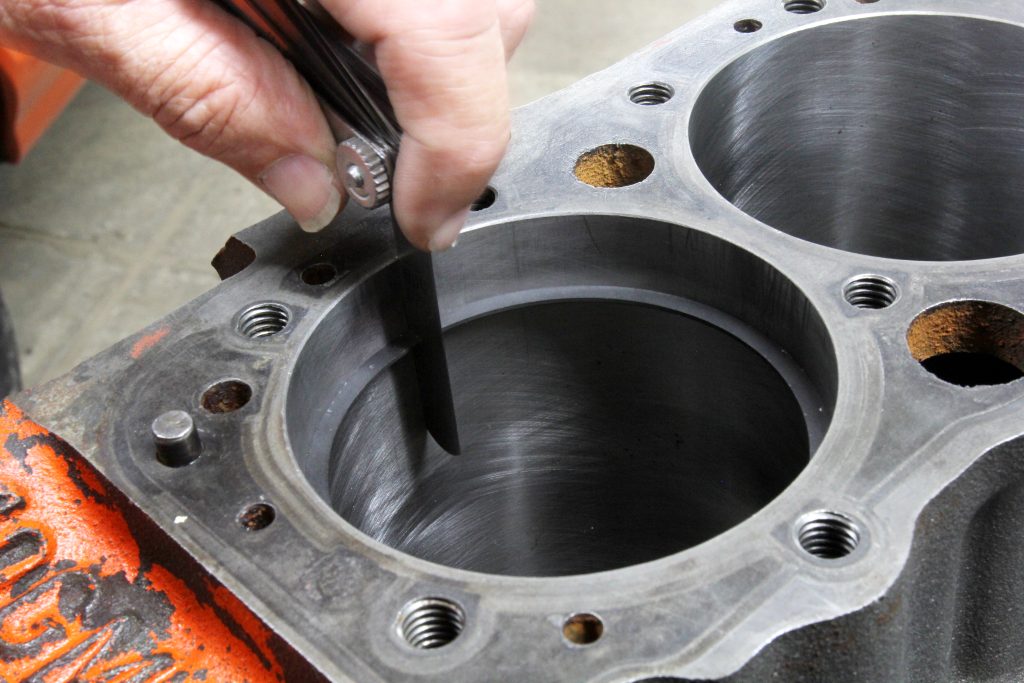 mechanic checking piston ring gap in engine cylinder bore