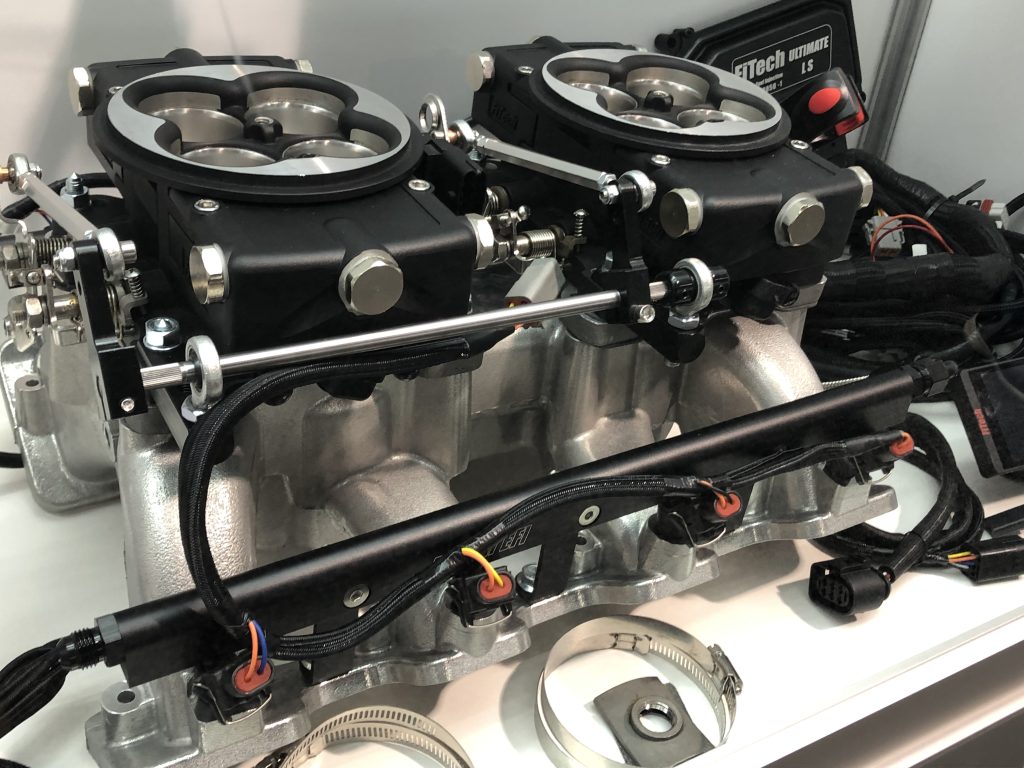 pair of efi throttle bodies atop an intake manifold on display at SEMA 2022