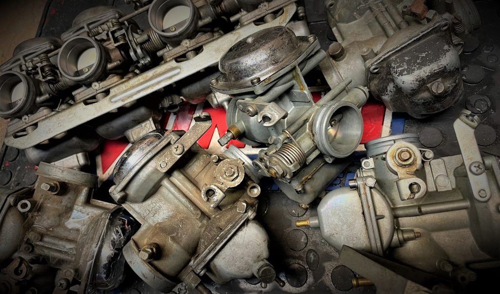 stack of old carburetors on a workbench