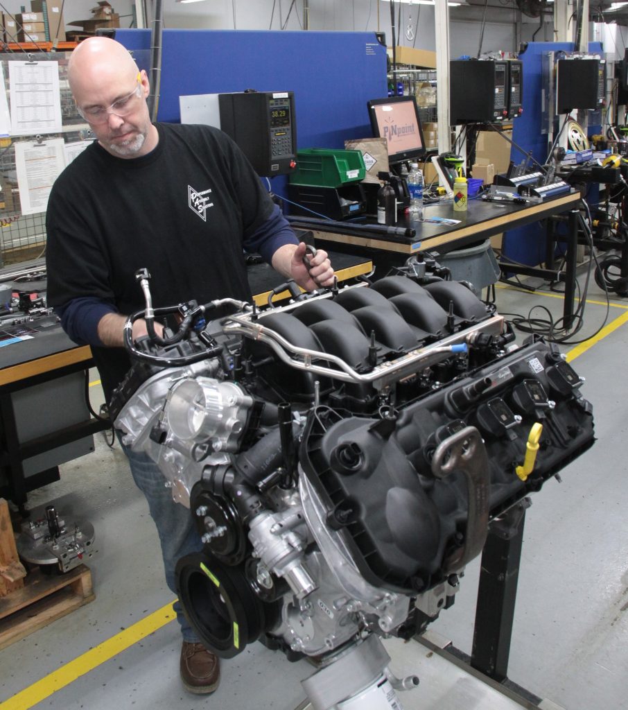 man working on ford performance coyote crate engine on stand
