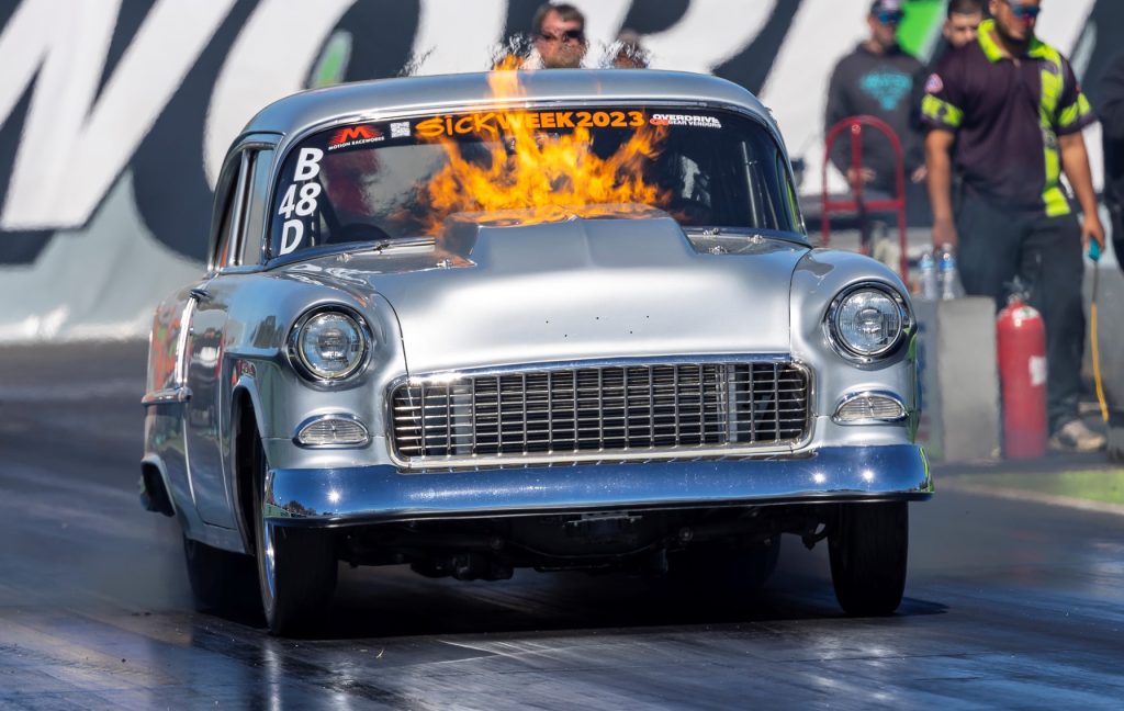 1955 chevy with flames shooting from hood during drag race launch