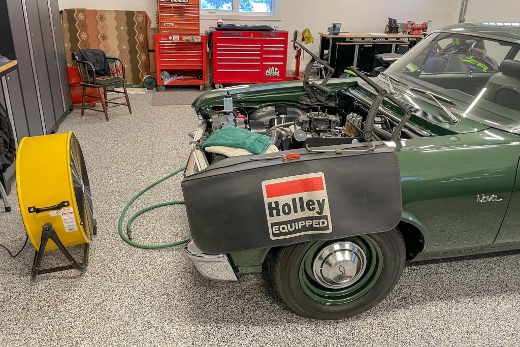 green Chevy nova project in garage with fan blowing across engine