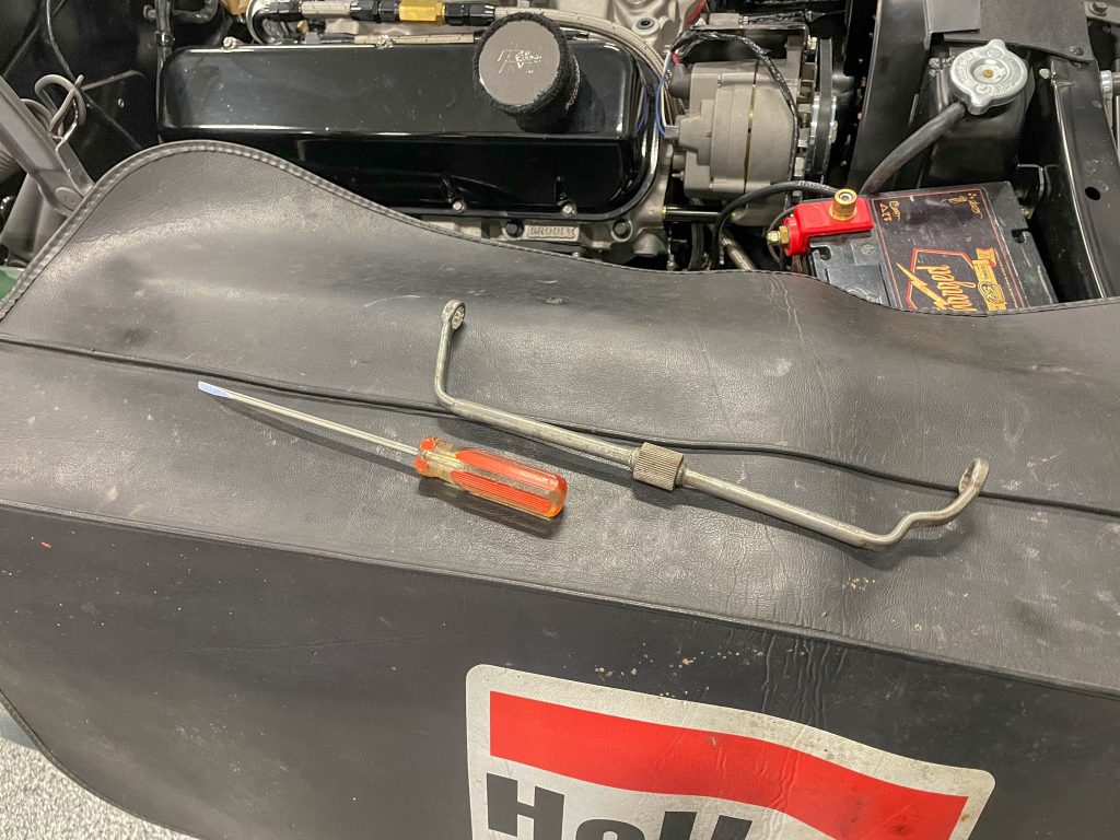 screwdriver and engine distributor wrench laying on a fender cover