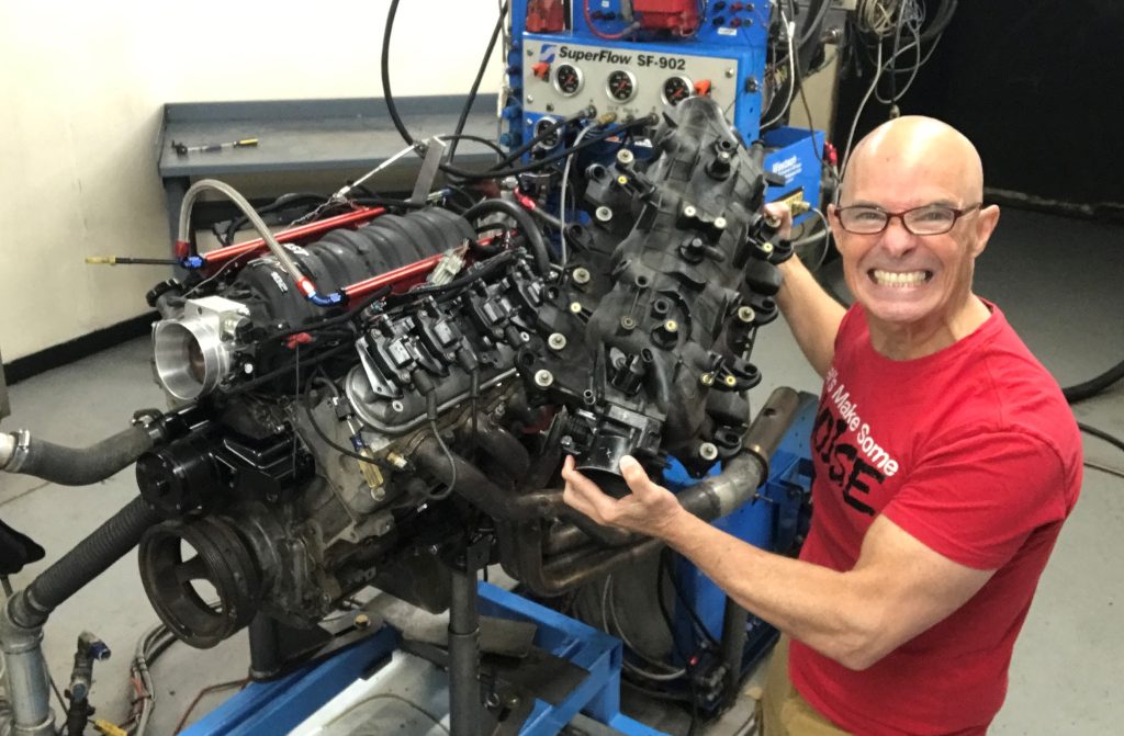 richard holdener holding an intake manifold near a GM ls engine on a dyno