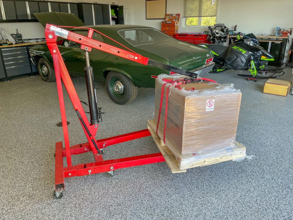 engine hoist lifting a heavy large box in a garage