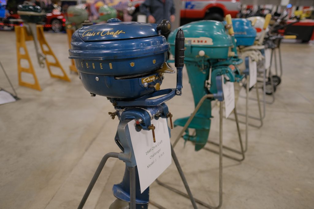 Chris craft and other vintage marine outboard motors displayed at a car show