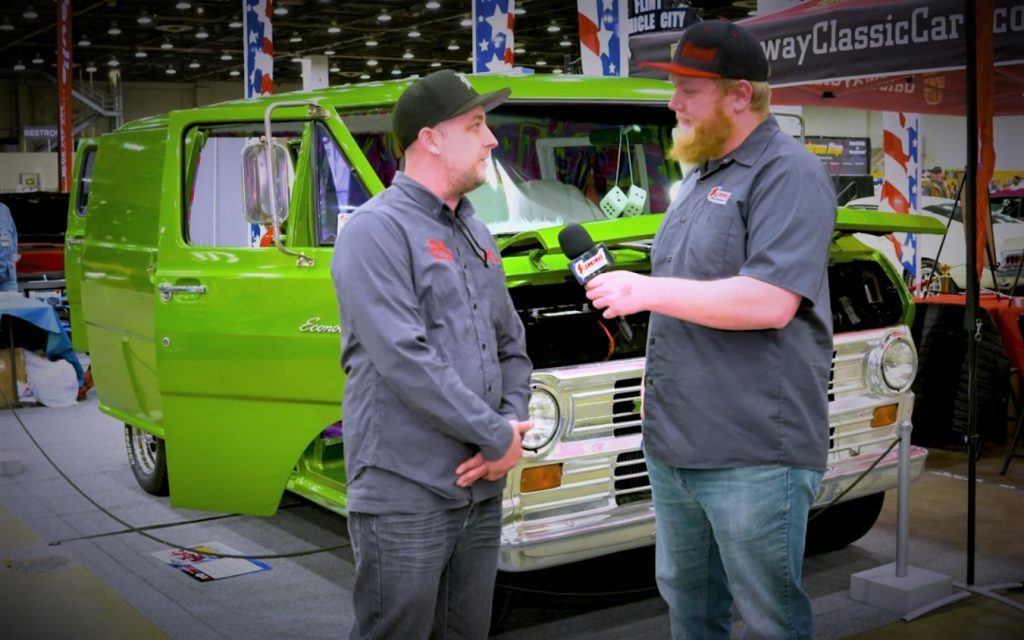 Two men talking in front of a custom ford Econoline van at a car show