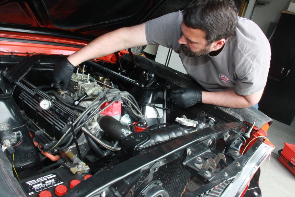 man installing holley 4150 carburetor on a ford mustang engine