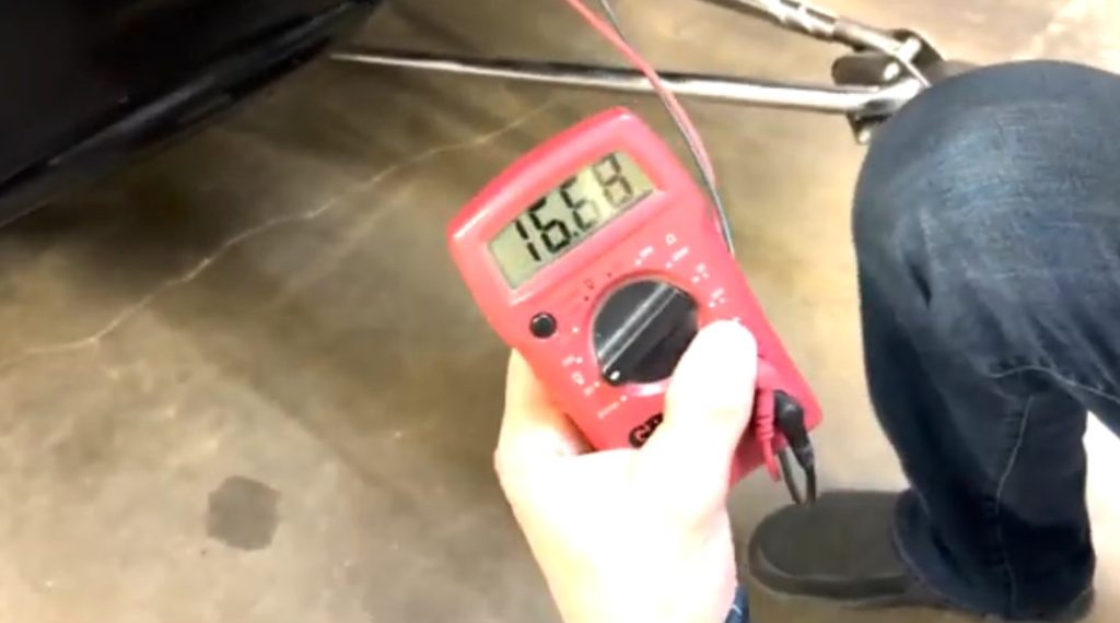 View of an electrical multimeter testing a vehicle battery voltage