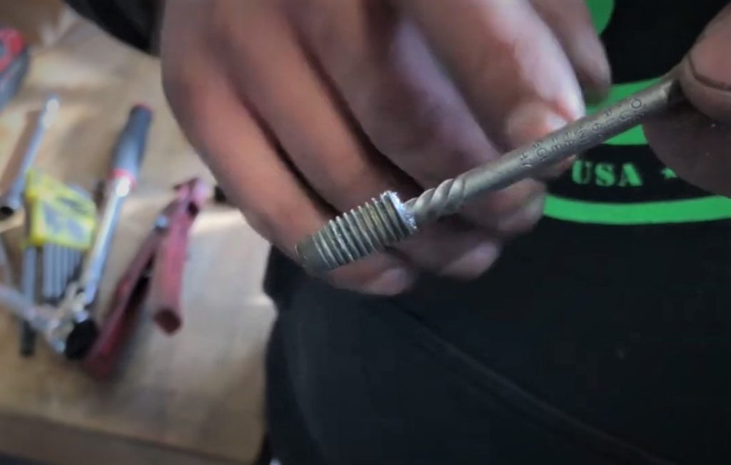 Man holding a broken bolt removed with an extractor tool