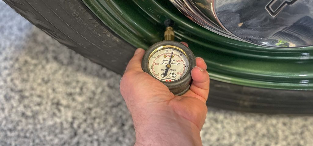man checking tire pressure psi on an old car