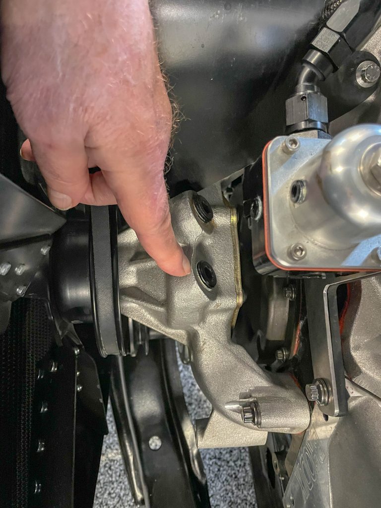 man pointing to water pump outlet installed on engine