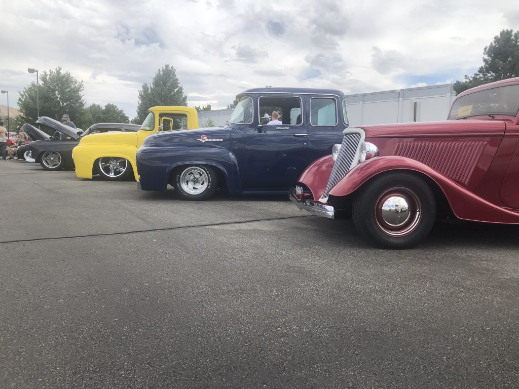 row of classic cars and trucks at a cruise in