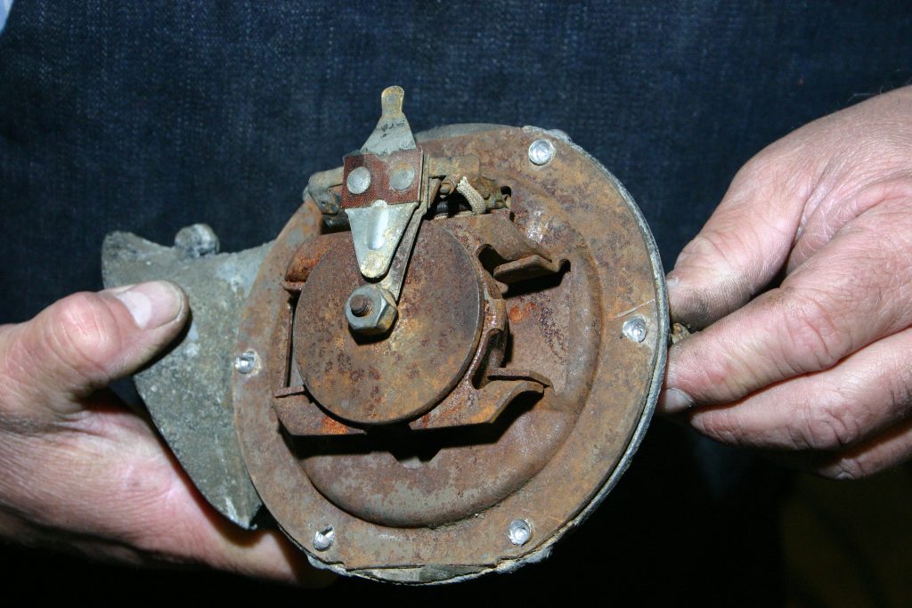 man disassembling an old vehicle car horn