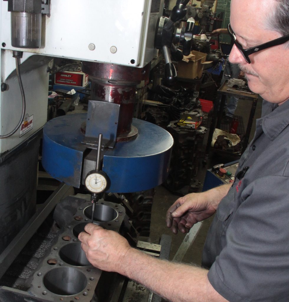 machinist pressing cylinder sleeves into an engine block