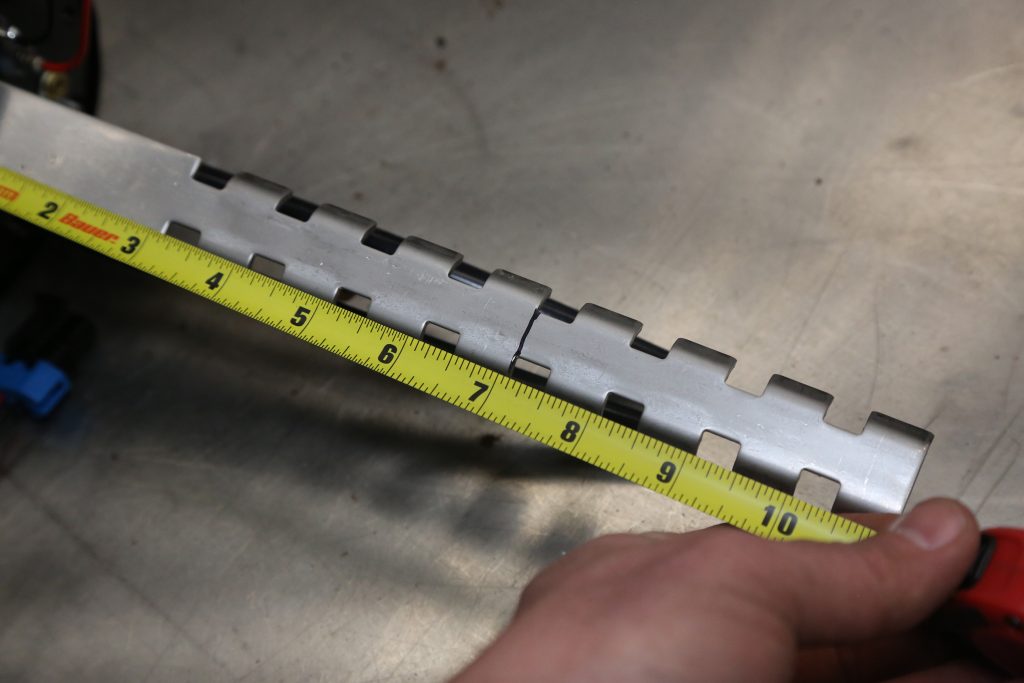 man measuring a metal bracket