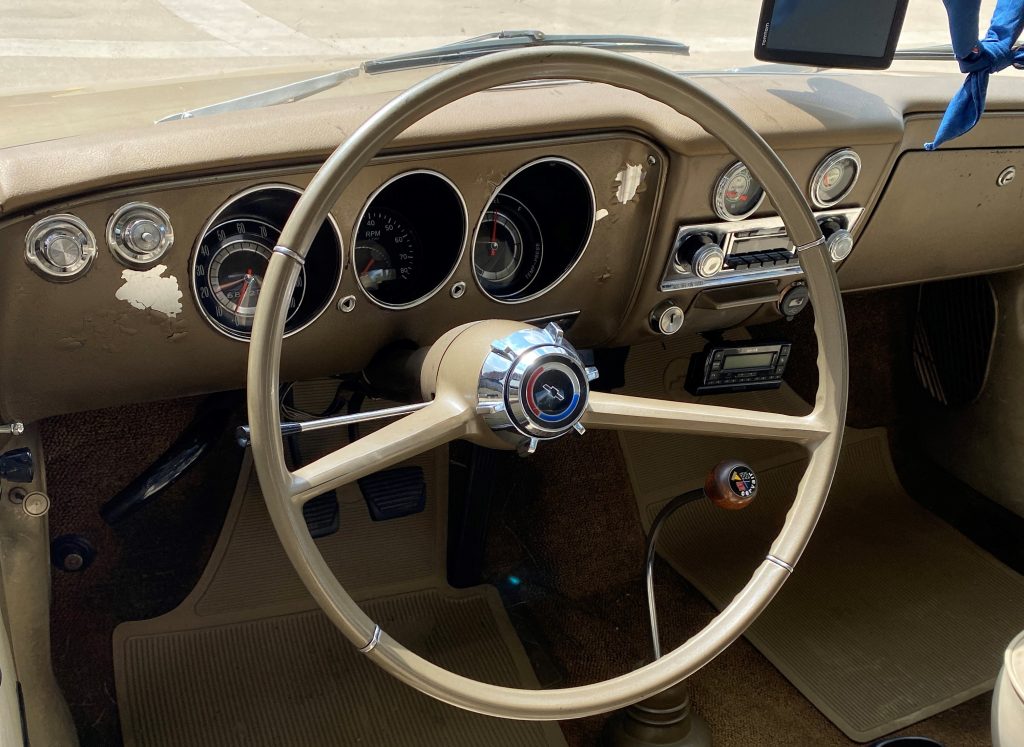 steering wheel and interior shot of a gold 1966 corvair