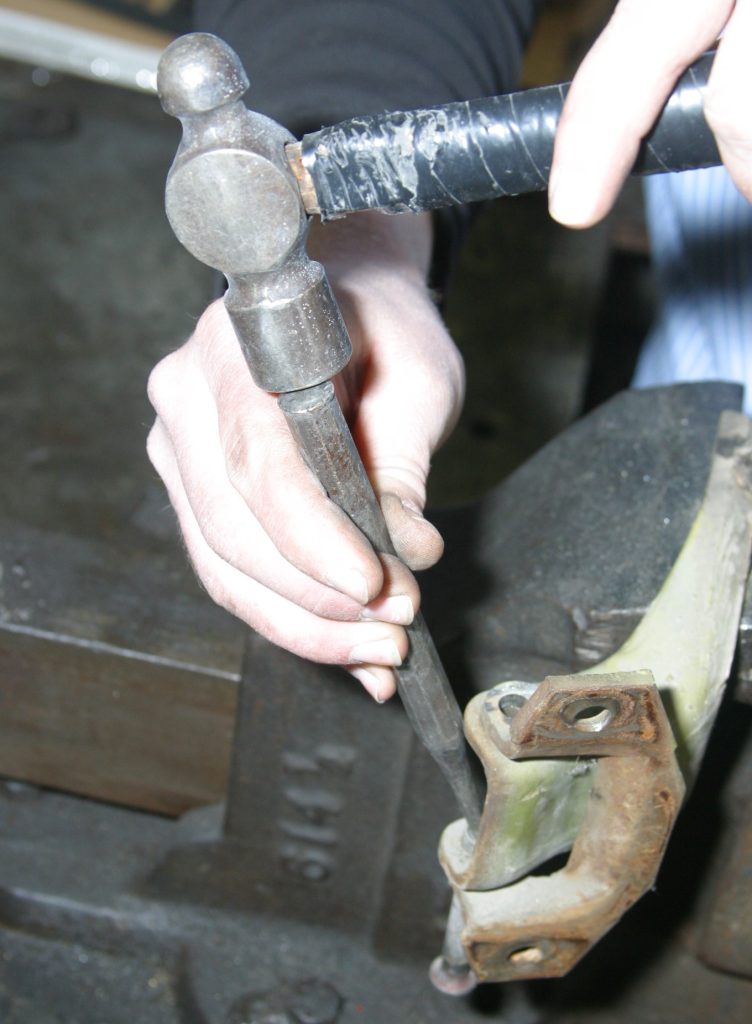 using a hammer and punch to remove a car door hinge pin