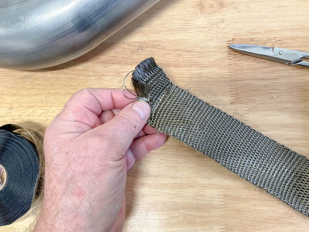 man holding exhaust heat shield wrap prior to cutting