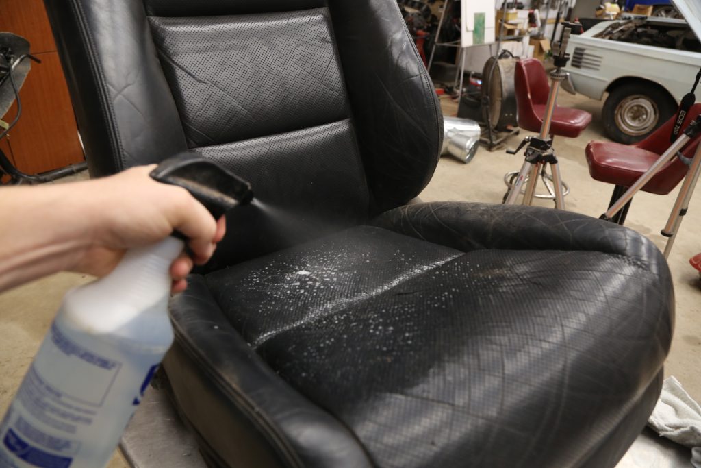 spraying a car seat with cleaning solution