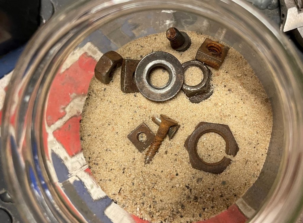 rusty hardware in tumbler drum with sand