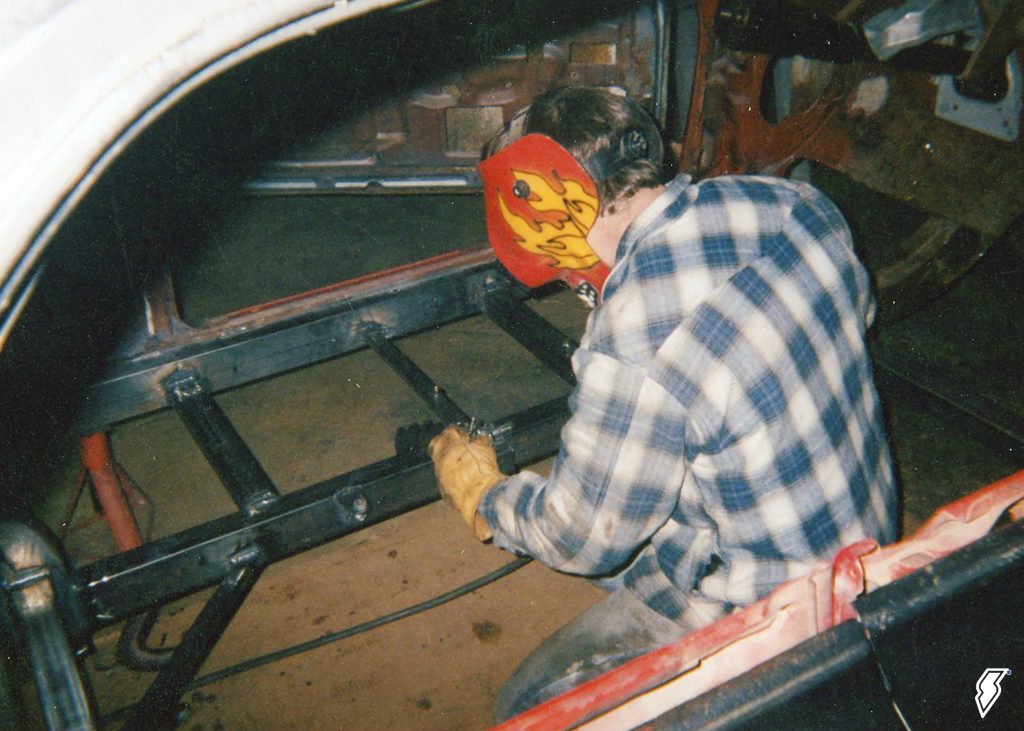 man welding frame & floor support in a 1962 impala drag car