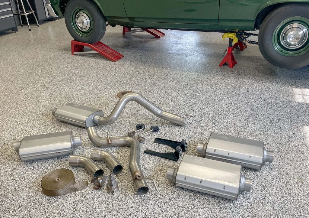 a collection of exhaust parts near an old muscle car