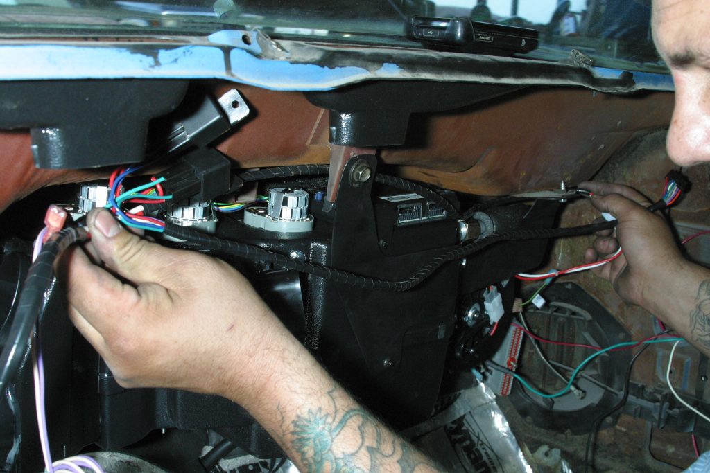 man installing a wire harness on a vintage air A/C system