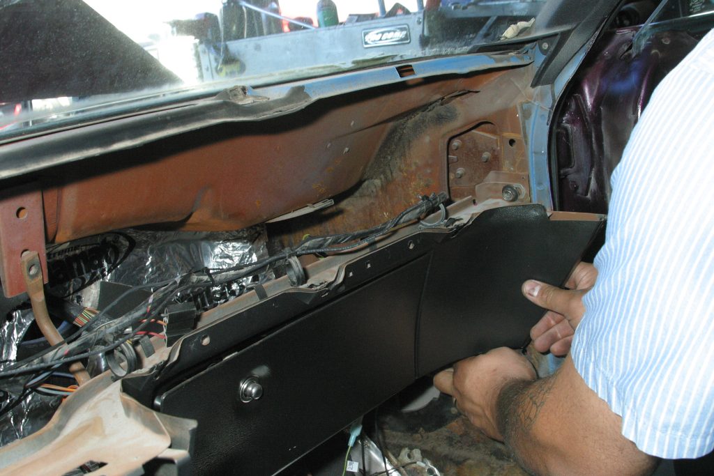man removing dash panel from a vintage ford mustang