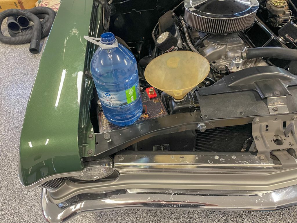a jug of distilled water resting on a radiator support