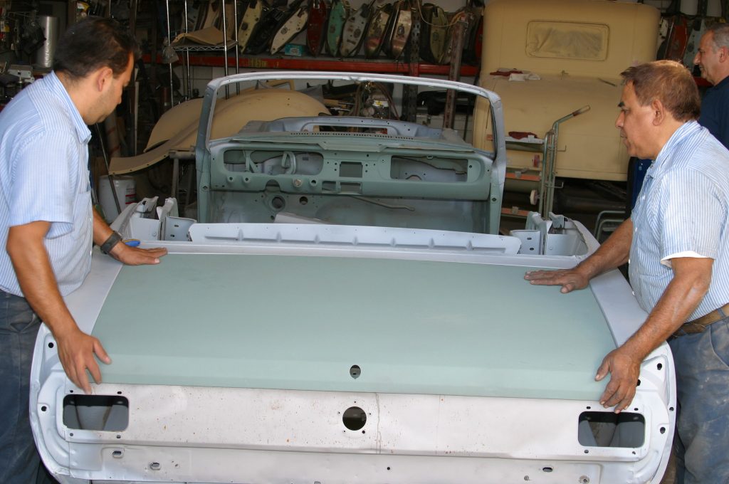 men fitting a replacement trunk lid onto a vintage mustang