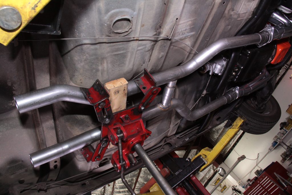 jacking up an exhaust section under a classic muscle car