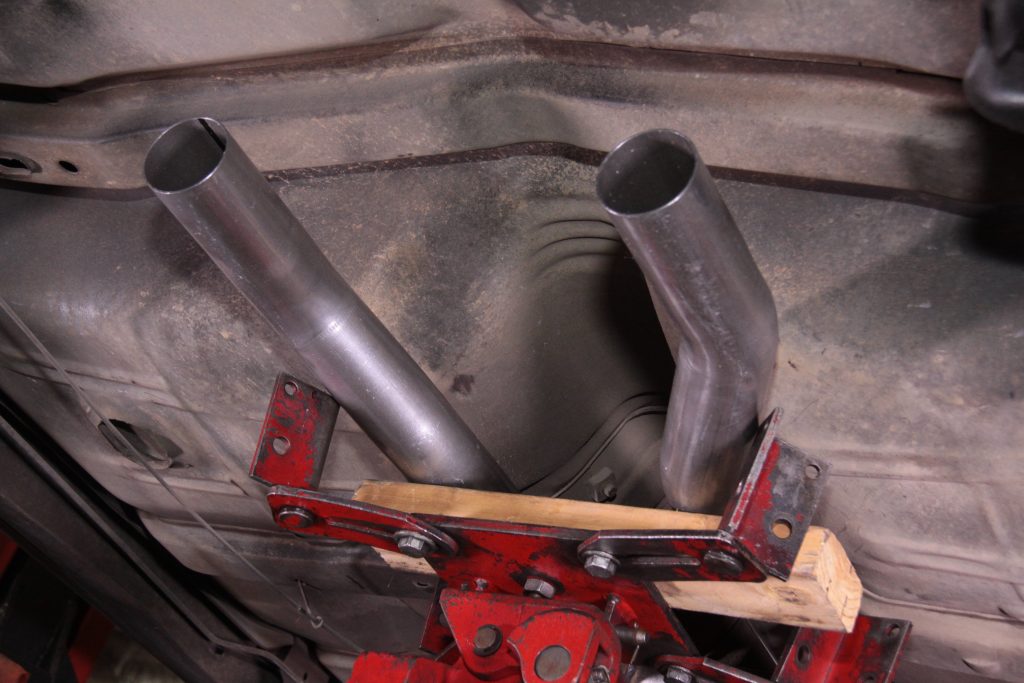 a pair of bare exhaust pipes under a vintage car