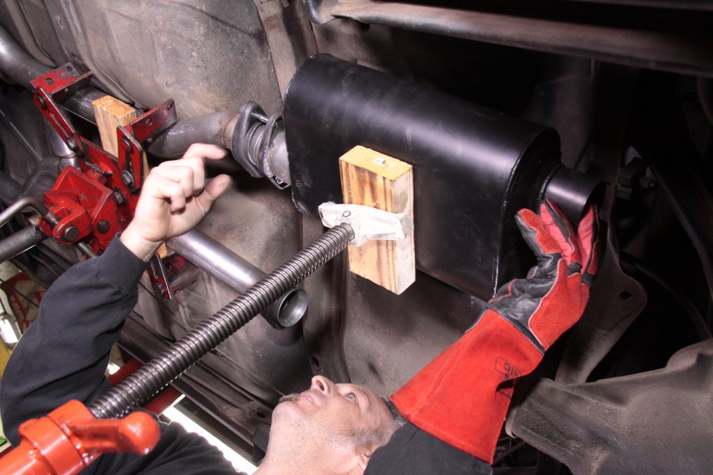 jacking up a muffler onto a car prior to welding