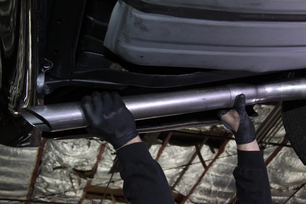 fitting exhaust tips onto a classic muscle car