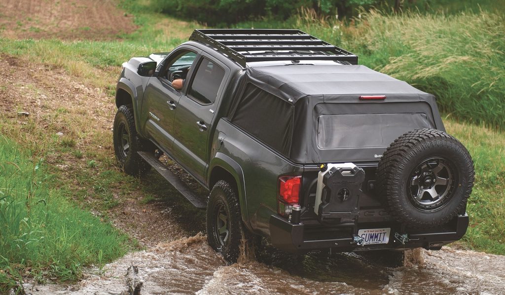 Rear view of a toyota tacoma climbing out of a creek off-road