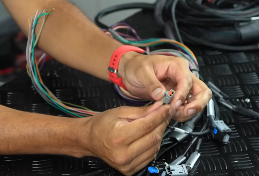 man holding a connector an a vehicle wiring harness
