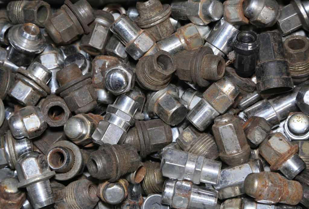 pile of old, used, mixed lug nuts in a bin