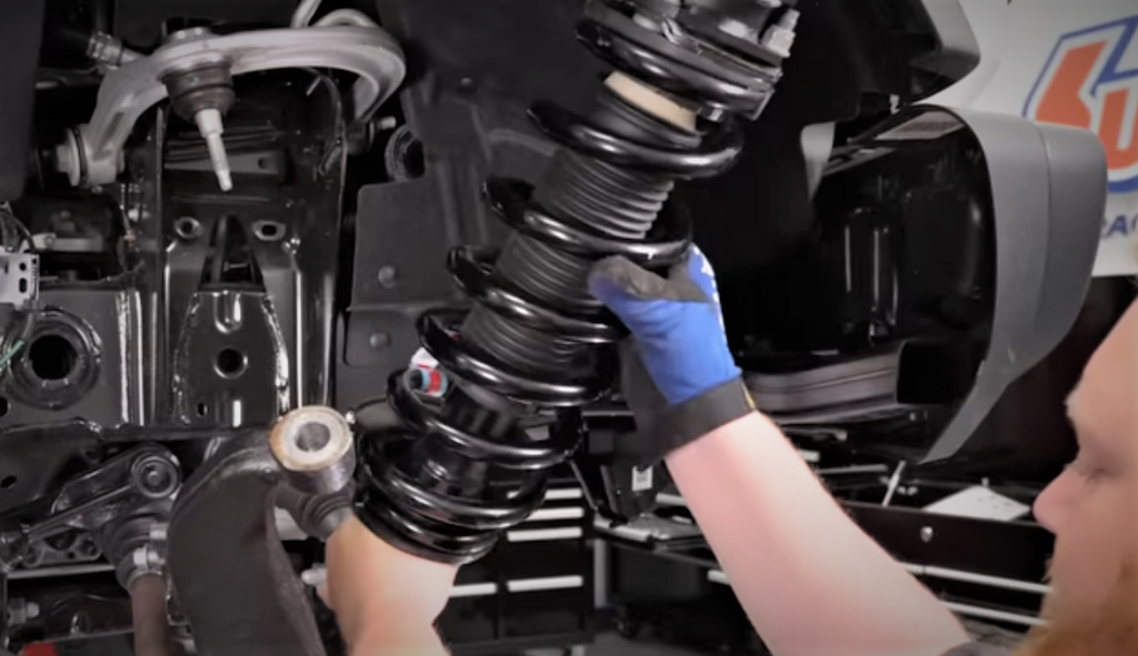 man installing a strut shock combo in a ford bronco