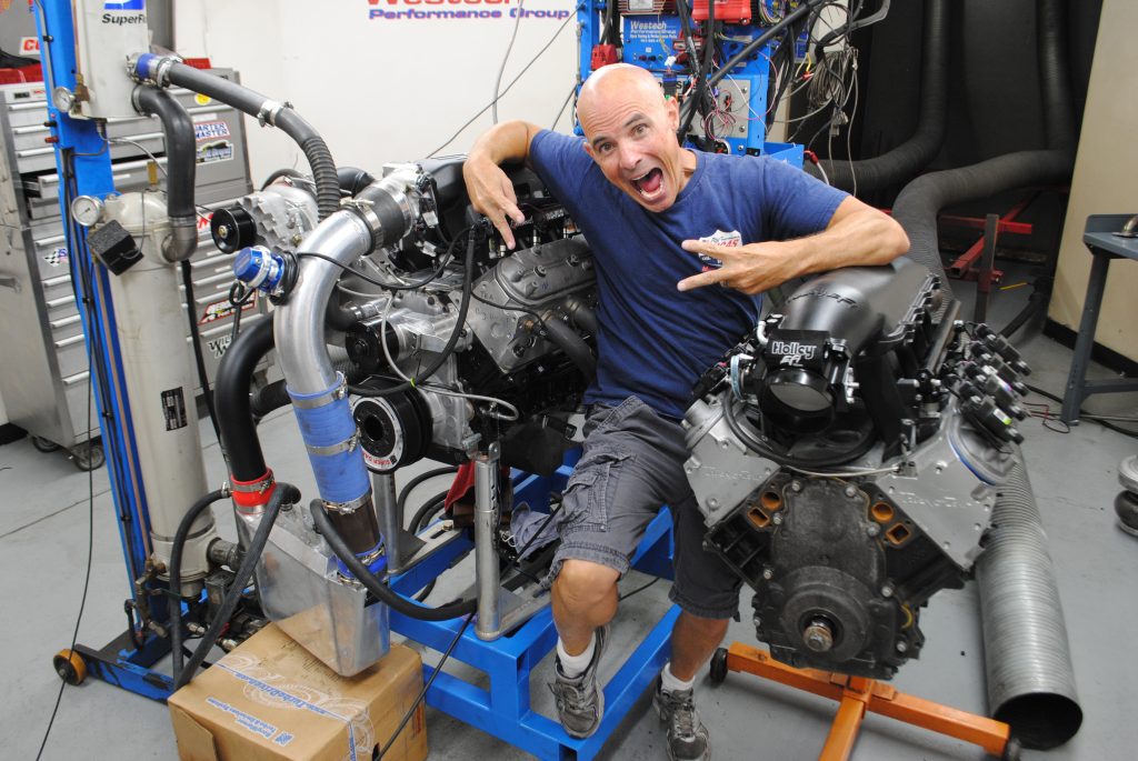 man standing between two engines in a dyno room
