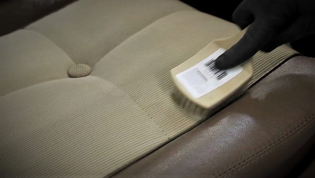 using a brush to remove stain from a vintage car seat