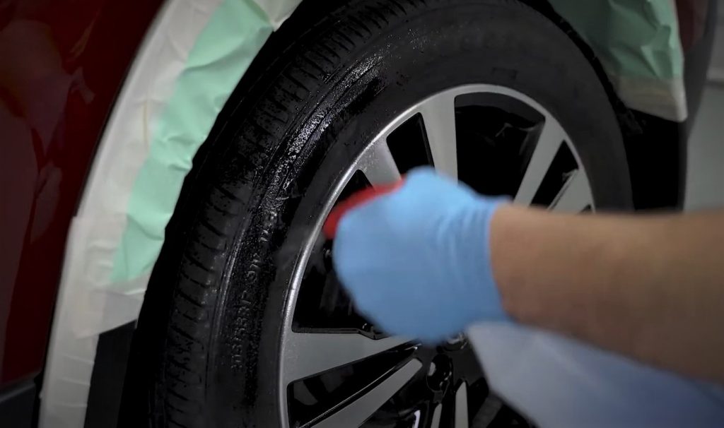 man spraying tire cleaner onto a wheel