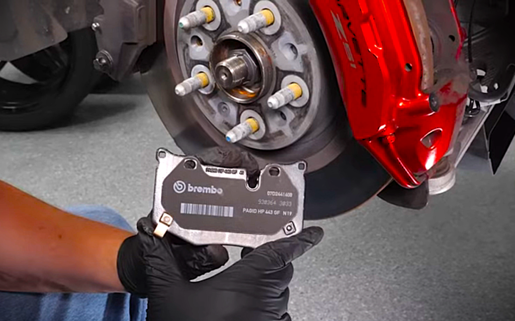 man holding brake pad near a brake rotor